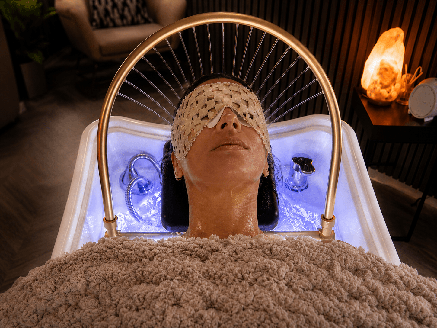 Guest receiving a Cloud 9 hydro head spa beneath the gold halo and illuminated basin