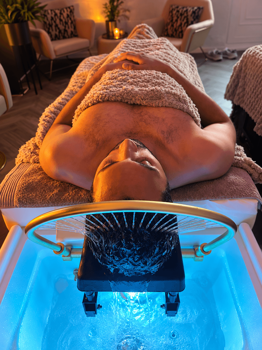 Male guest receiving a Cloud 9 Esquire head spa treatment beneath the water halo